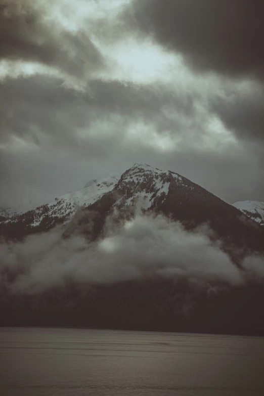 a big mountain covered in clouds above the ocean