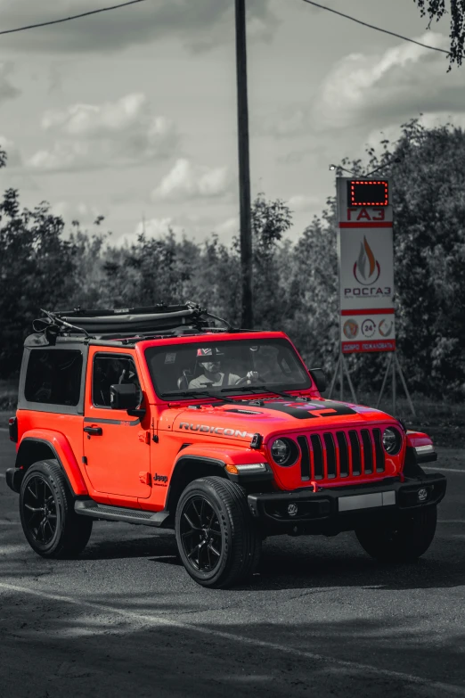 a red jeep parked in front of a gas pump sign