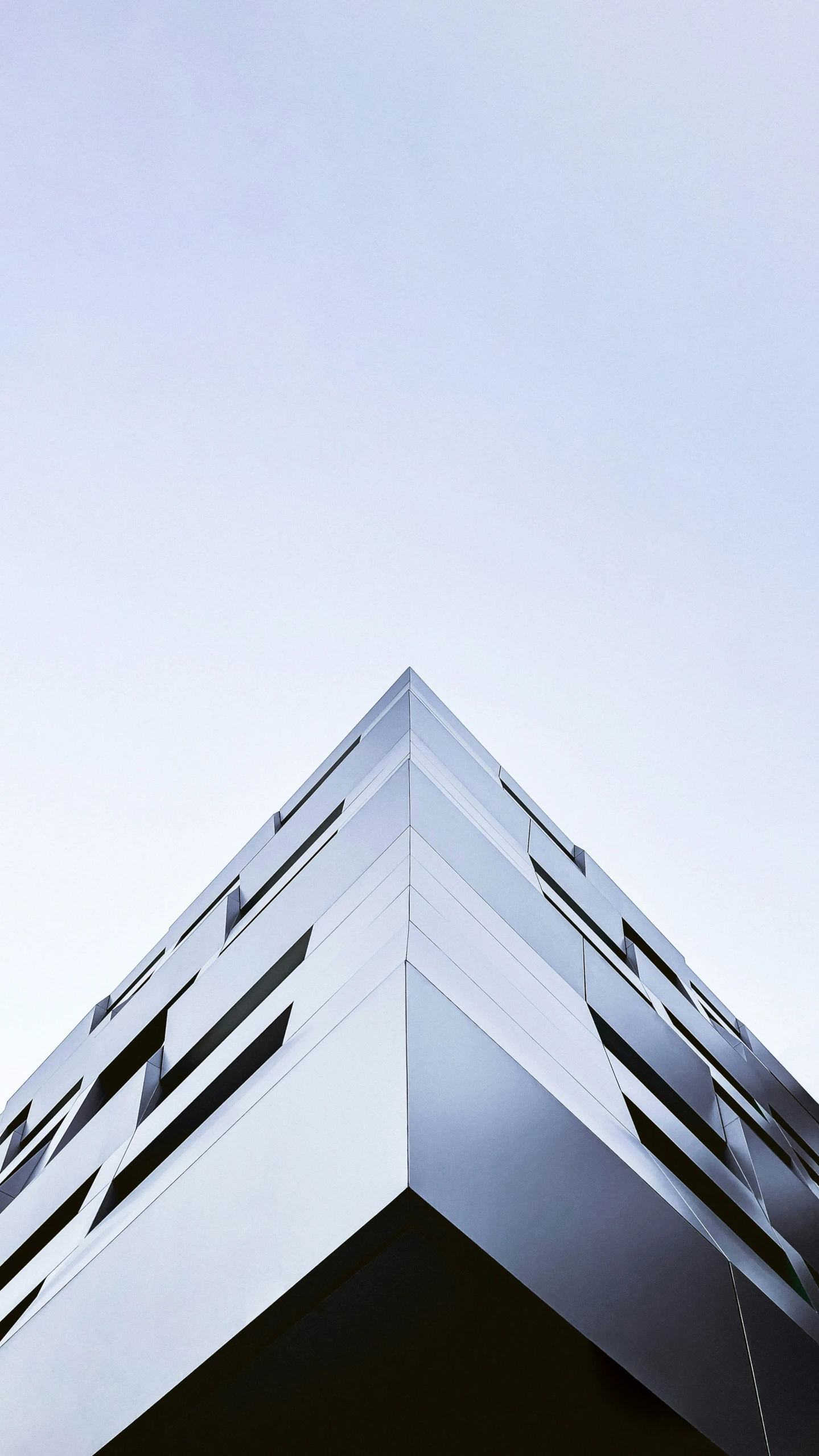 a tall white building with black balconies on top