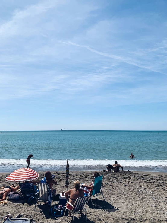 several people are sitting at the beach on a nice day