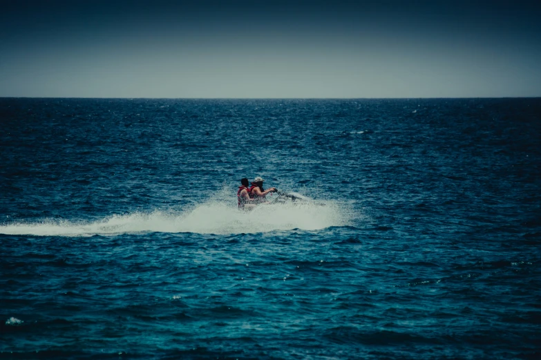 a person skiing across the ocean with other boats in the distance