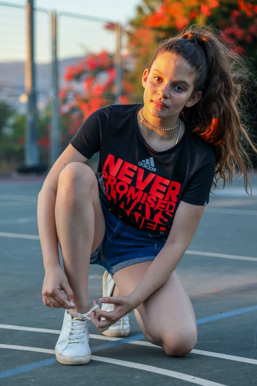 a woman is sitting in a parking lot and tying her sneakers