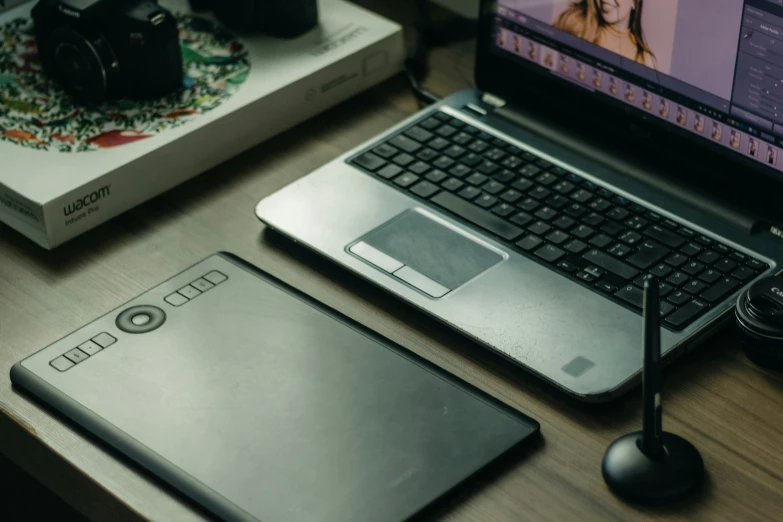 a laptop sits open next to a camera, notebook and digital camera