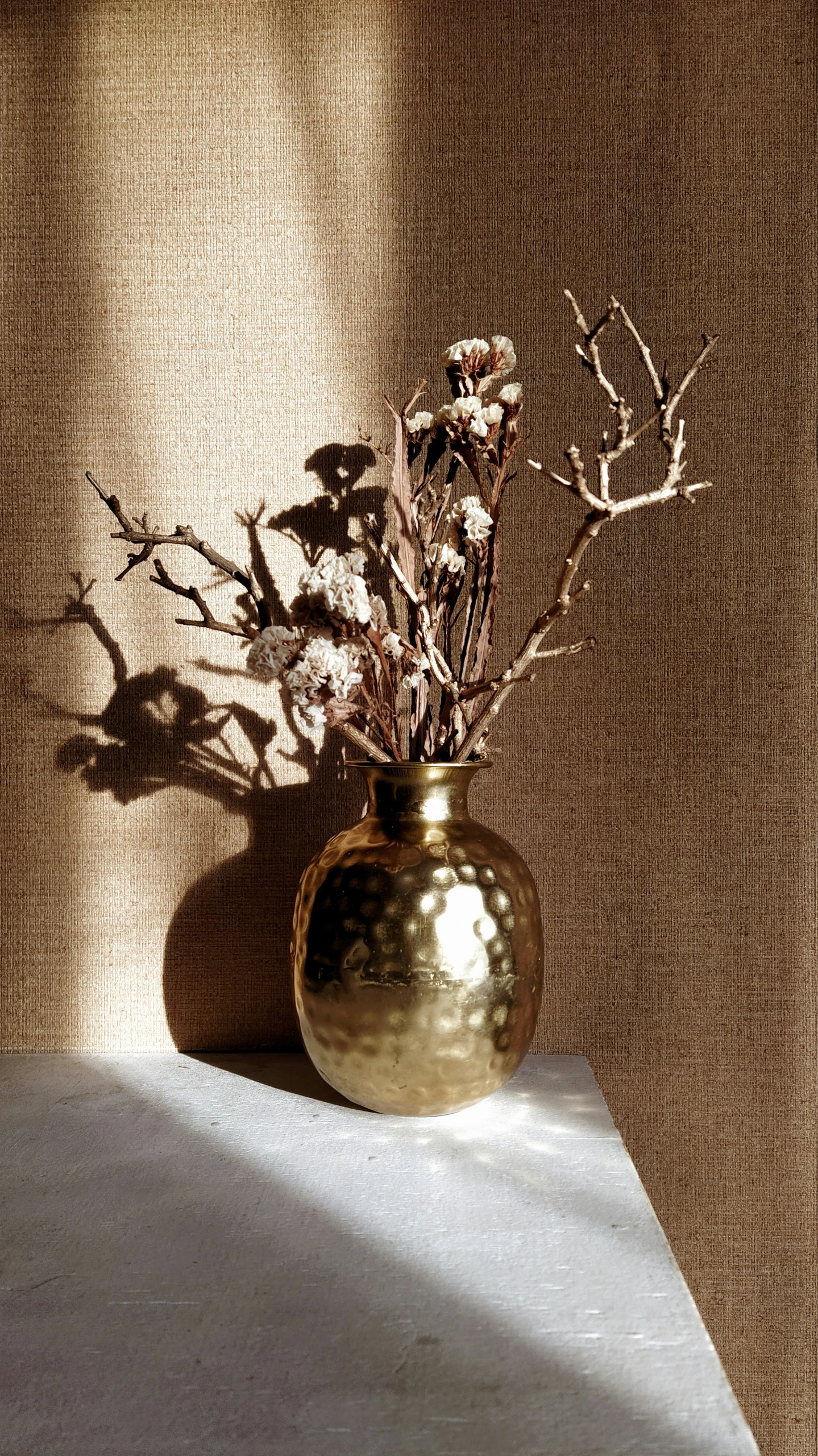 small golden vase sitting on table near wall