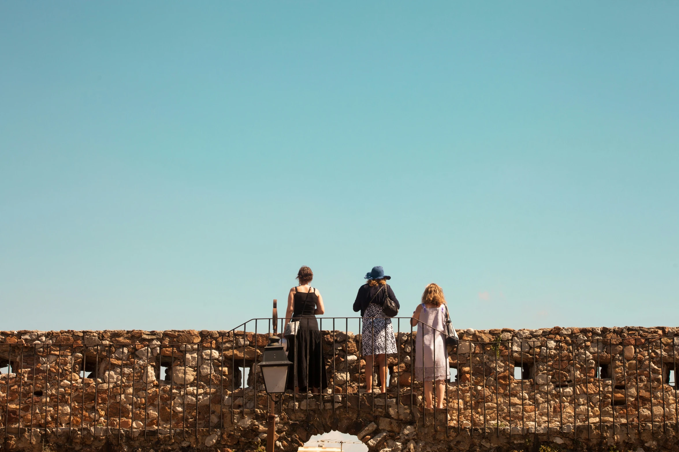 two people are looking out over a stone wall