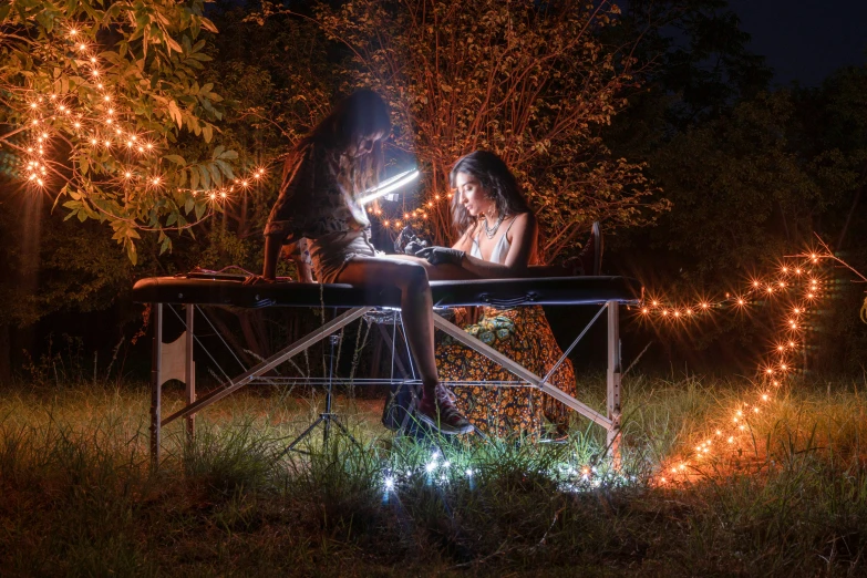 two people sit at a table looking down at a phone