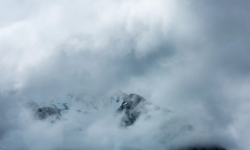 an airplane flying above a large mountain covered in clouds