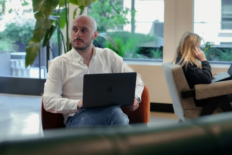 a man sits with a laptop in a business office