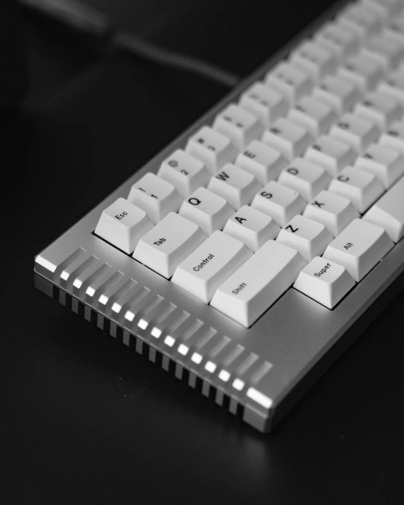 a keyboard sitting on a desk top with the keys white