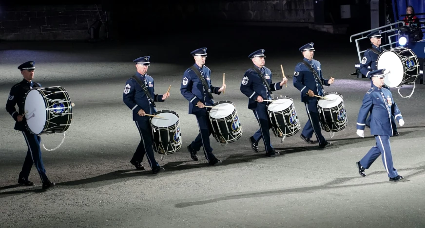 a group of young men walking across a field holding drums