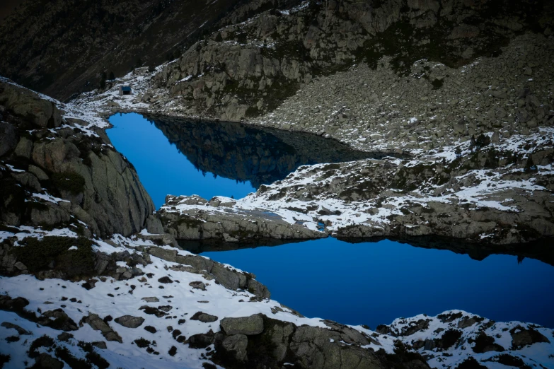 the snow covered mountains have small blue lakes near them