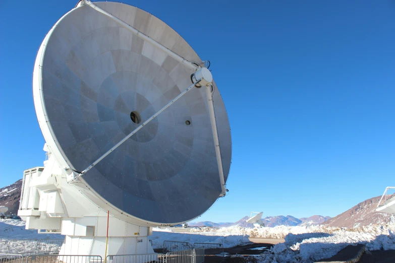 a large satellite dish sits on a snowy mountain