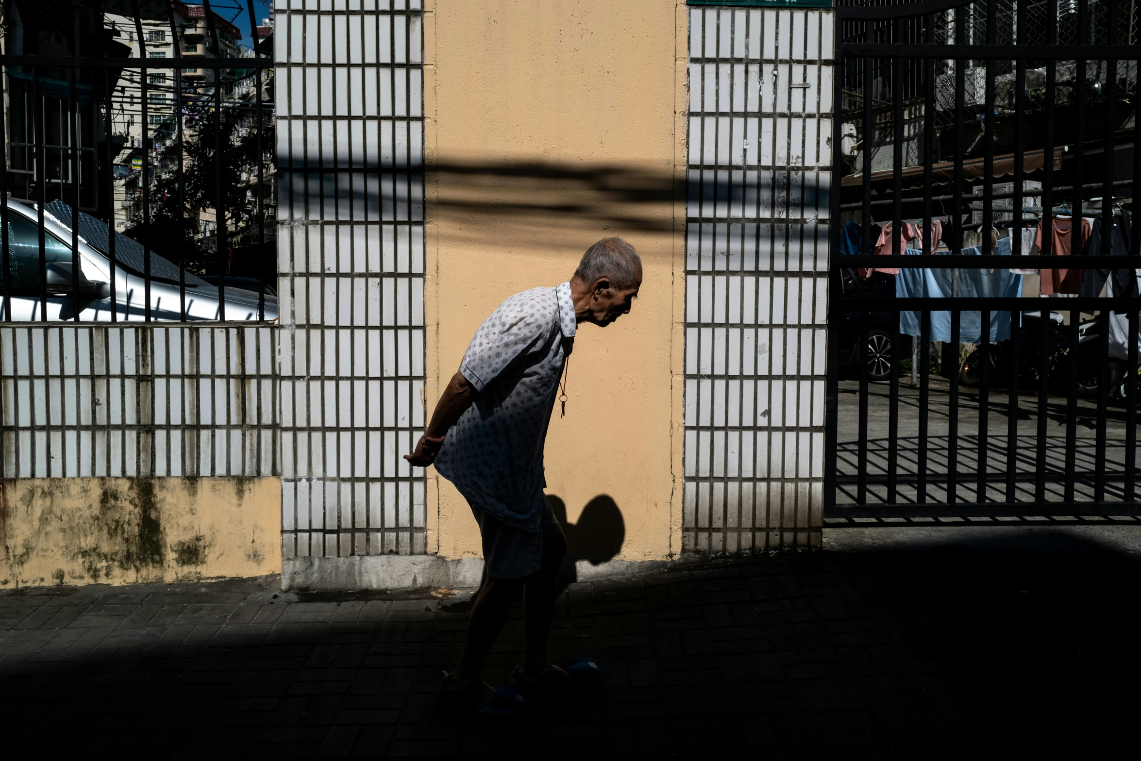 a man walking down a street next to a yellow wall