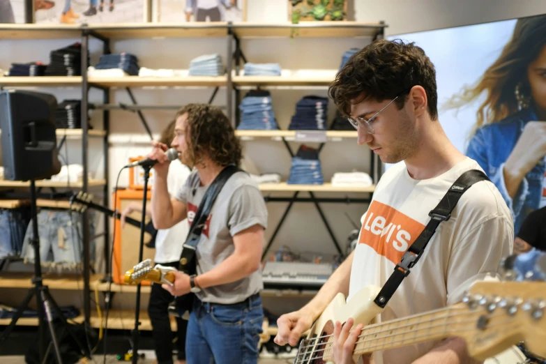 the young man is holding a guitar at the store