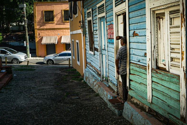 man standing on small wooden steps near multicolored old house