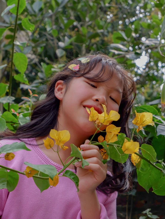 a little girl smelling some yellow flowers