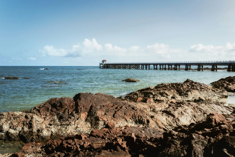 the sea with the water, rocks, and a large pier