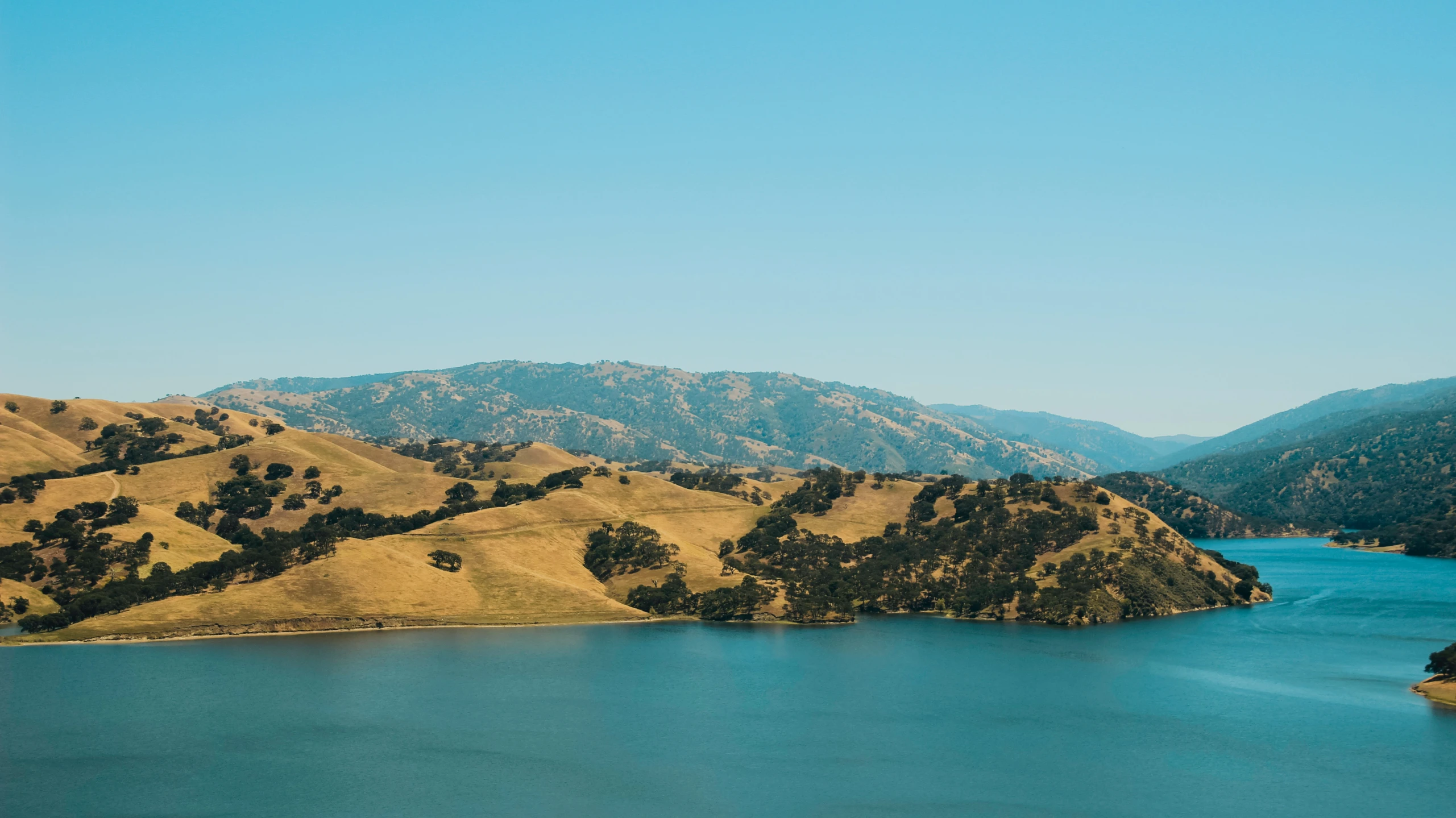 a lake surrounded by green hills and water