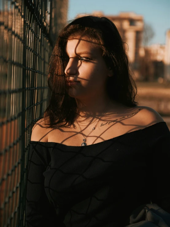 woman leaning against fence and looking out to the side