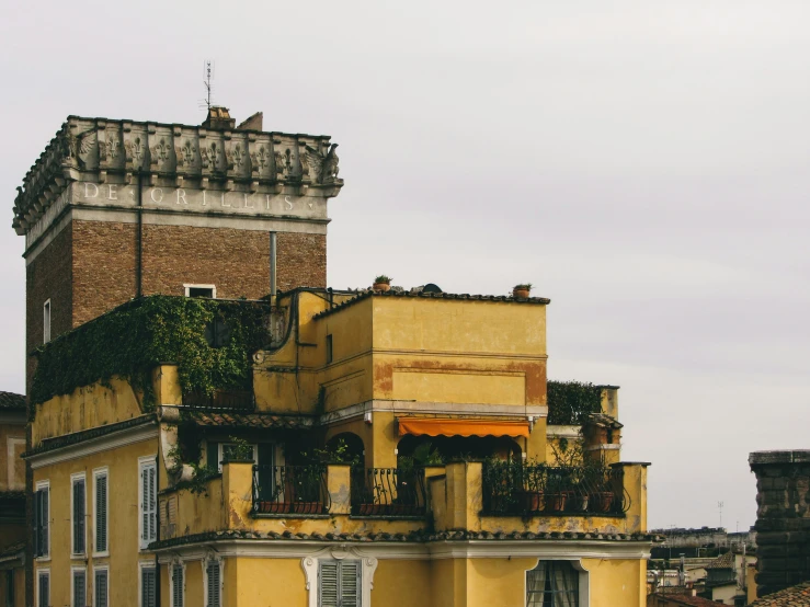 an old yellow building with vines growing on the balcony