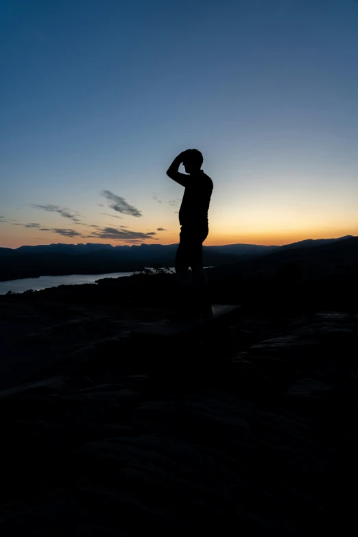 a man stands by himself in the dark with his hand on his head