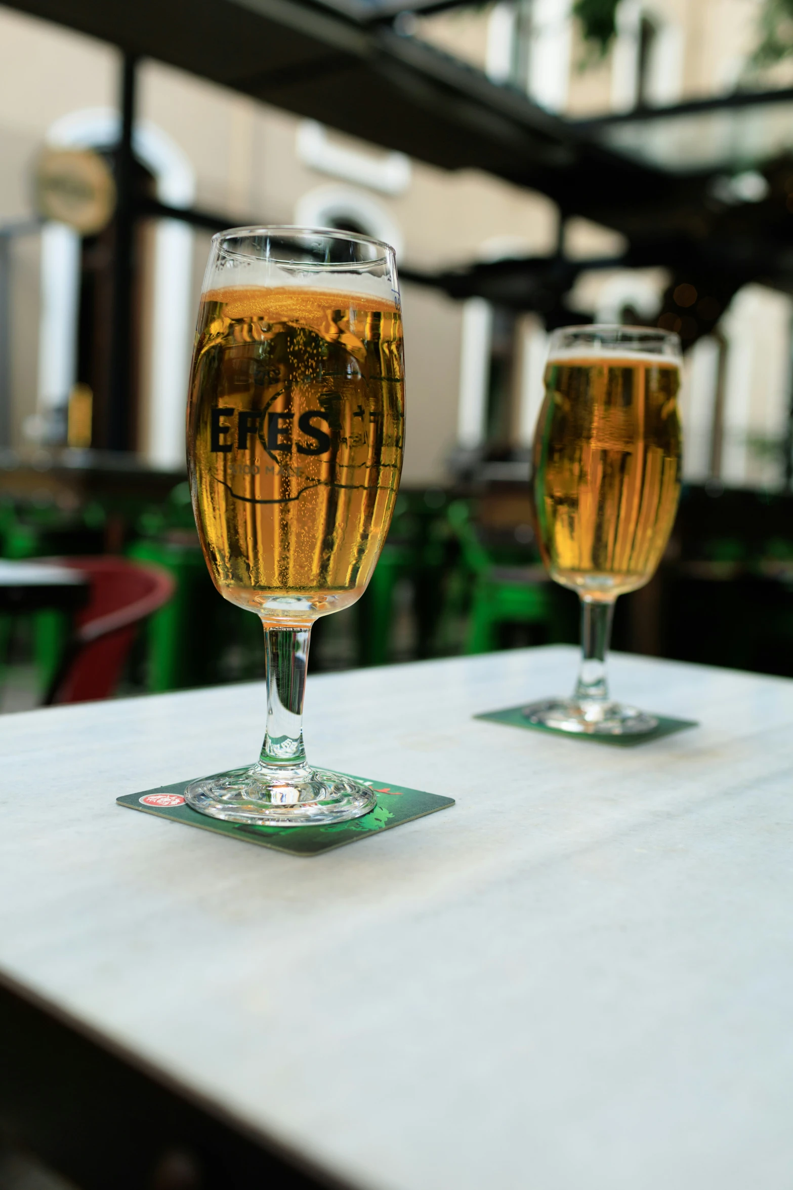 two glasses of beer sitting on top of a table