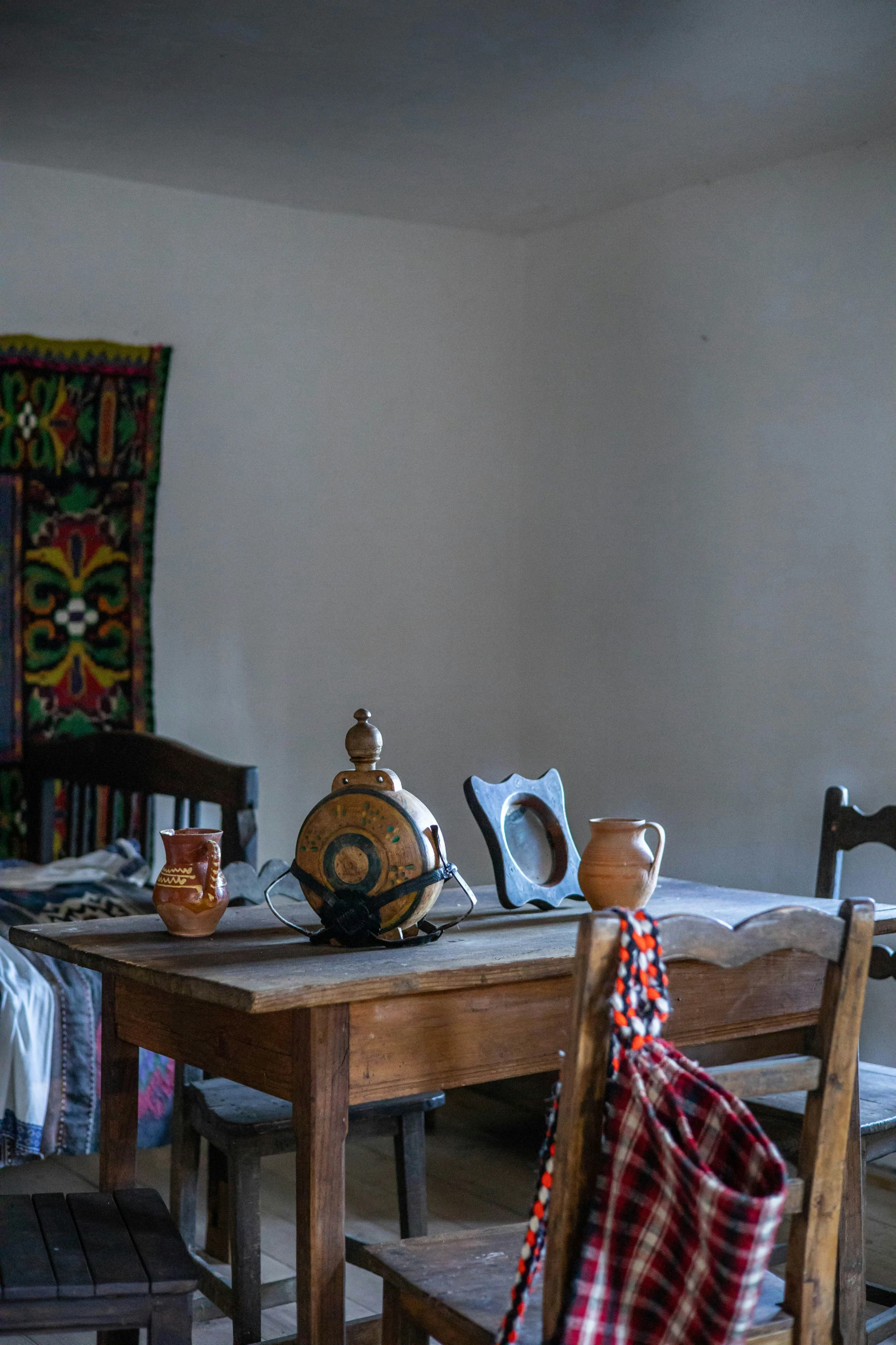 a small wooden table next to a chair and some kind of tapestry