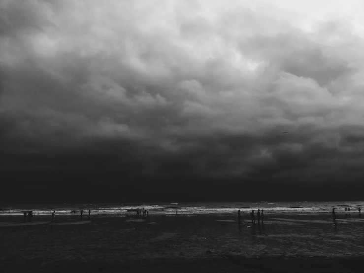 a group of people standing on top of a beach under a cloudy sky