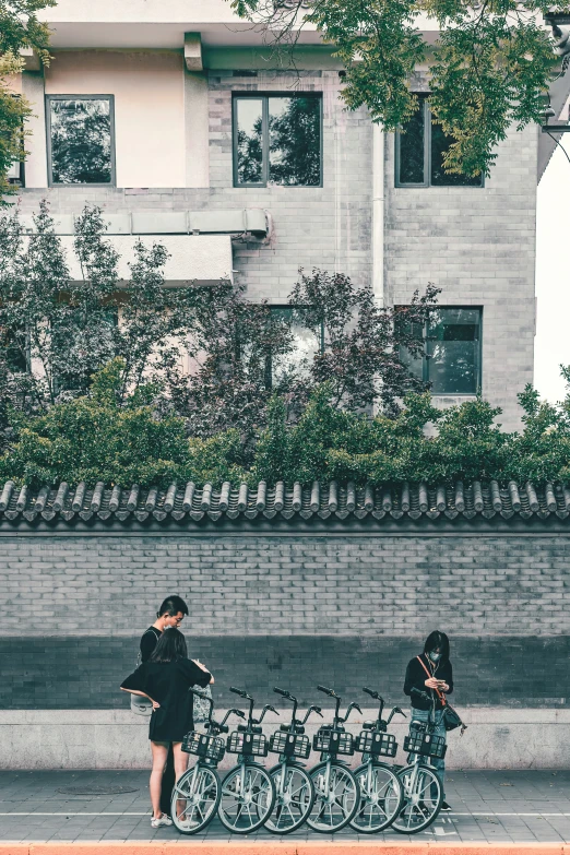 two people walking past a tall gray brick building