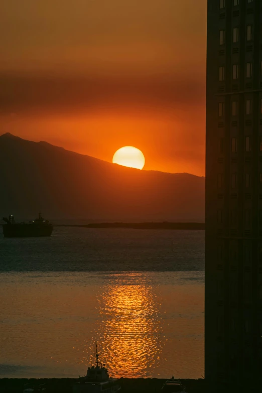 a boat sailing across the ocean in front of a sunset