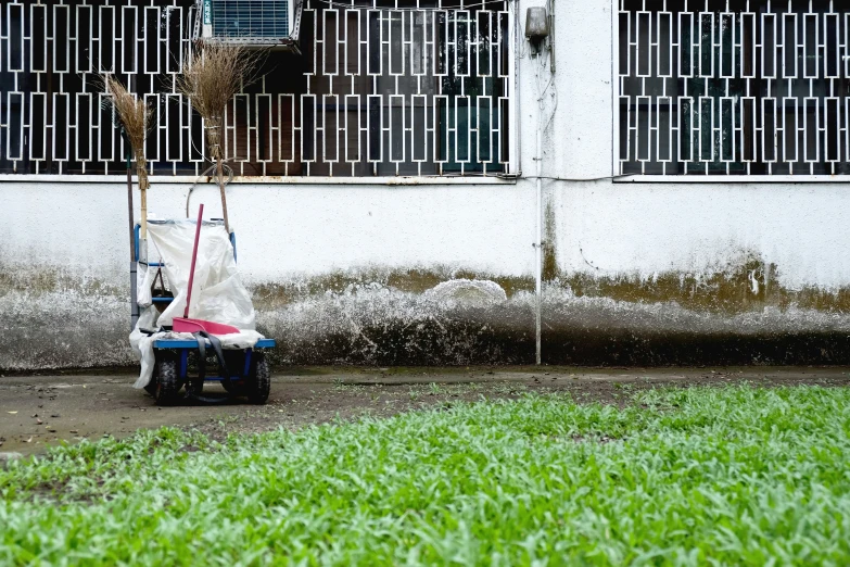 a building with grass and buckets on a cart