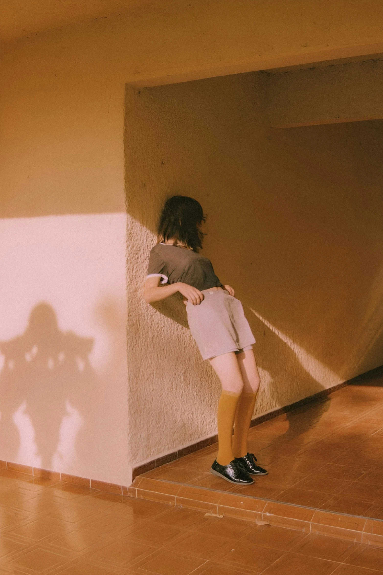 a young woman is standing by the wall in shorts and sneakers