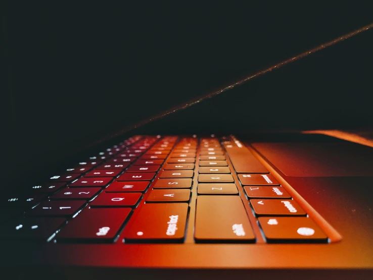 an orange computer keyboard illuminated in the dark