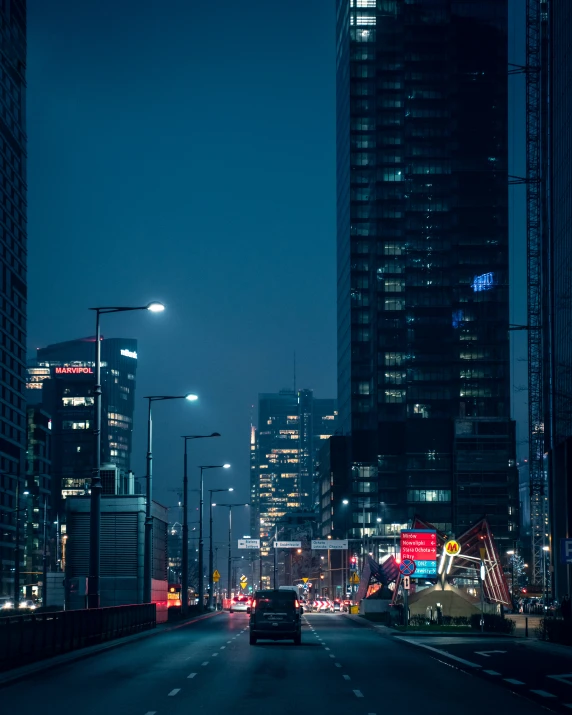 city with traffic on street at night near skyscrs