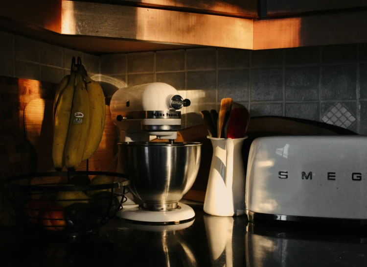 a kitchen counter top with a mixer, bananas and toaster oven