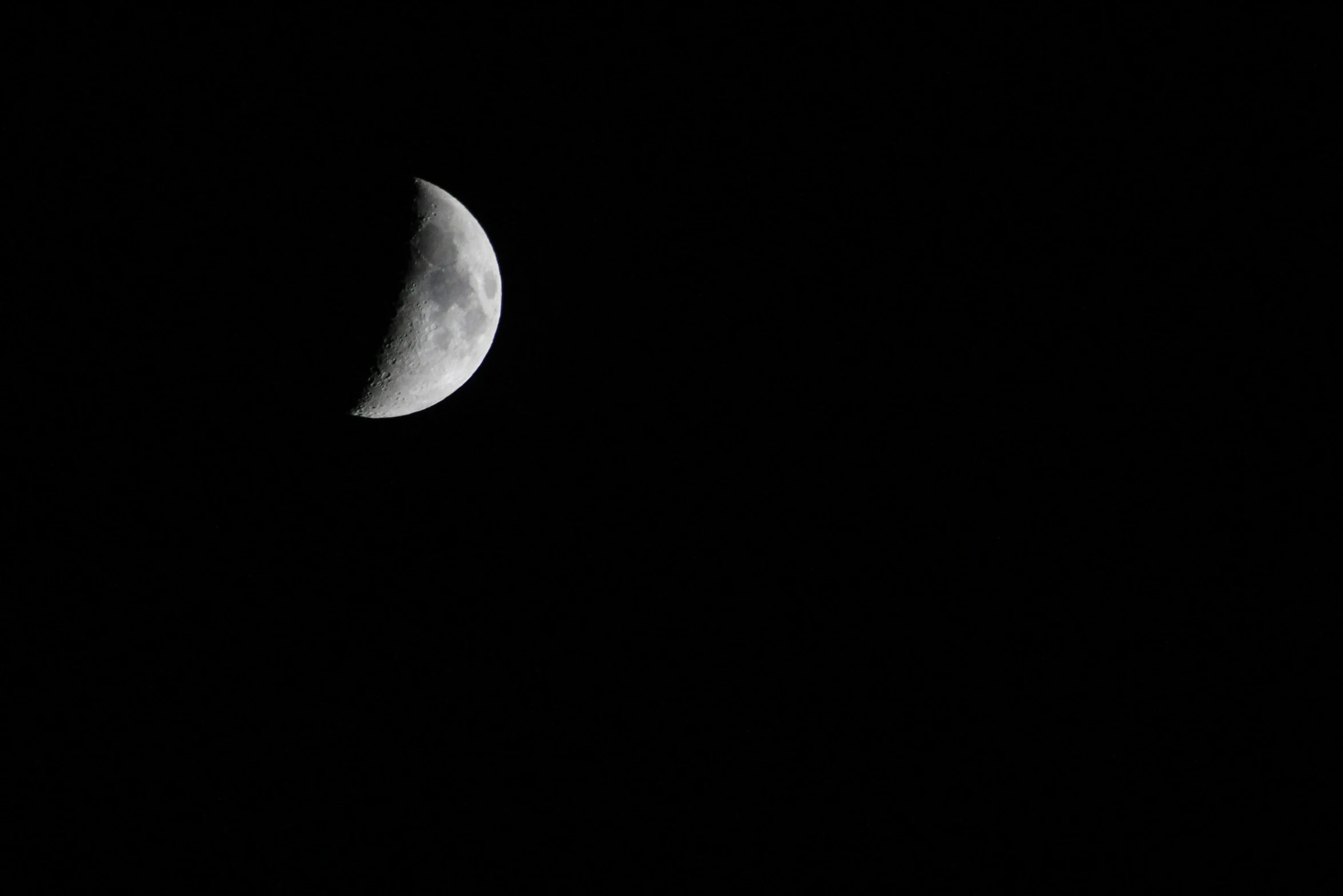 the moon is seen in a black night sky