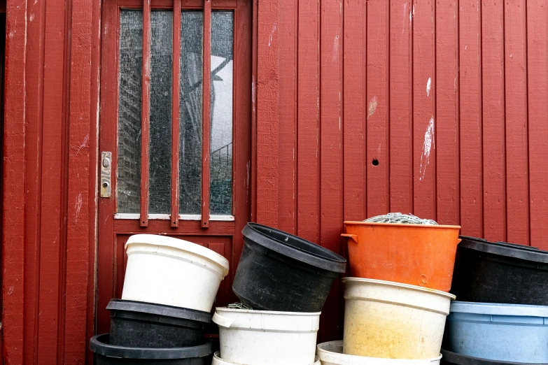 the large stack of trashcans is near a red door