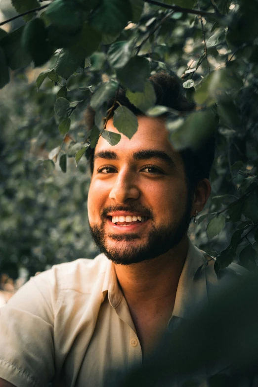 a man is smiling while standing under a tree