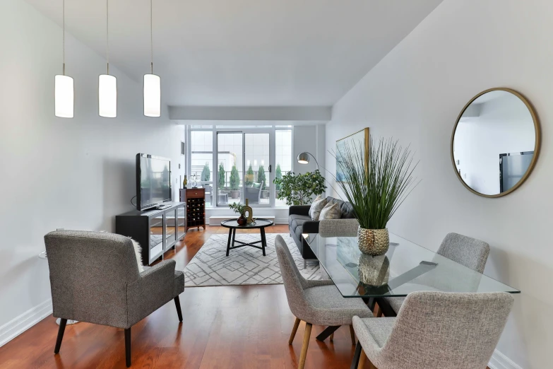 a dining room with glass table, wooden floor and mirrors on the walls