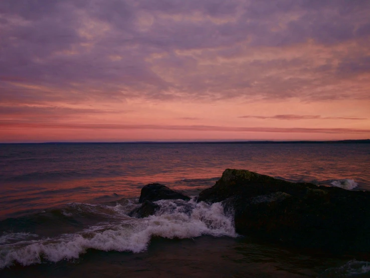 a person is standing on rocks near the ocean