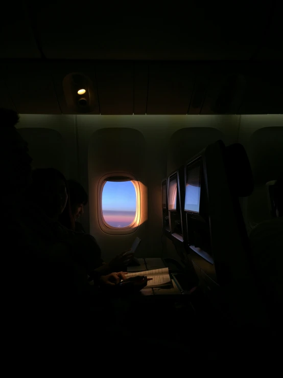 two people are looking out the window in an airplane at sunset