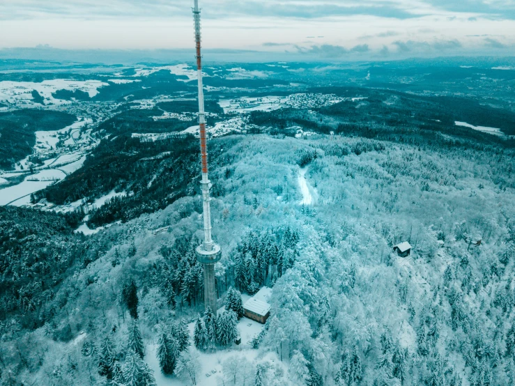 an aerial view of a radio tower in the middle of a snowy forest