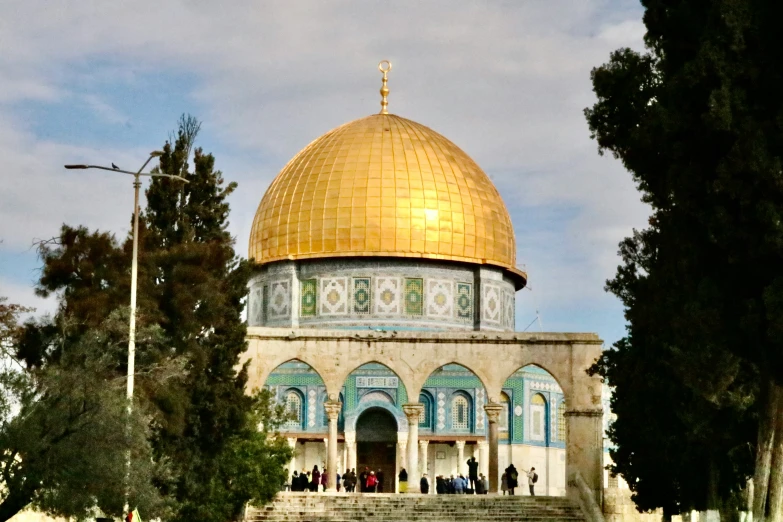 the dome is near several trees in front of some stairs