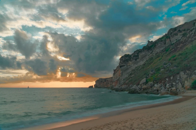 a large hill with the sun setting over water