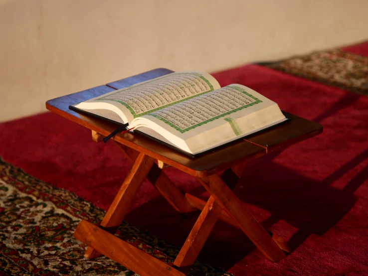 an open book on a wooden bench in front of a wall