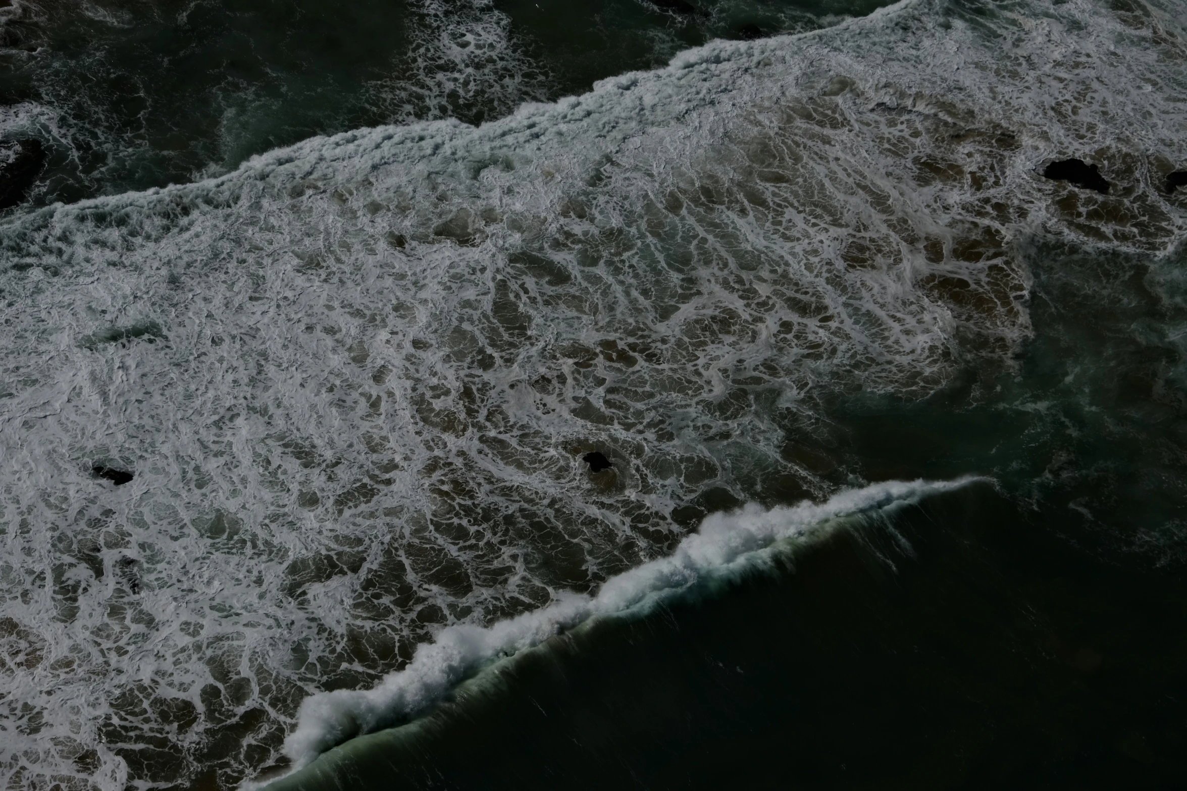 a wave is rolling into the shore near an ocean beach