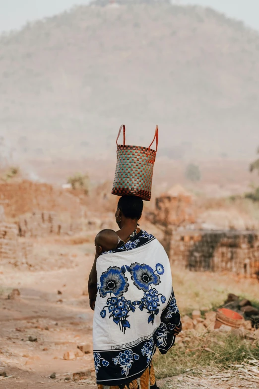 a woman carrying a basket on her head with an elephant skin on it