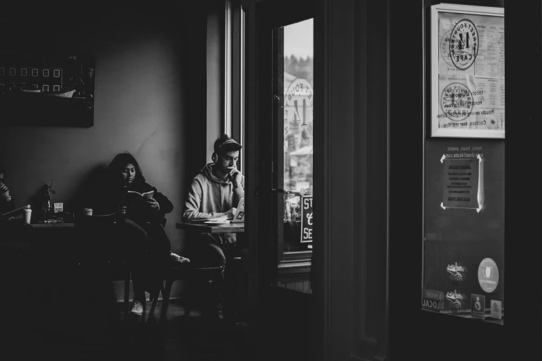 a man sitting at a table in front of another man looking out the window