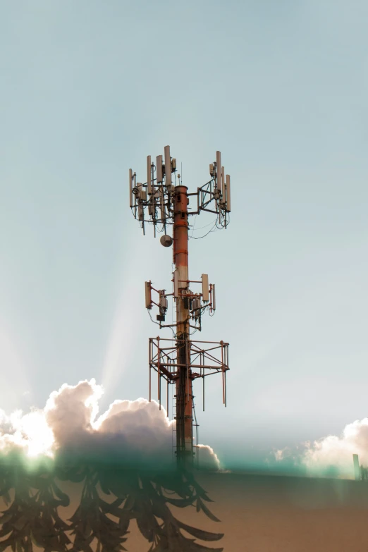 a cell tower is standing tall in the sky with some clouds