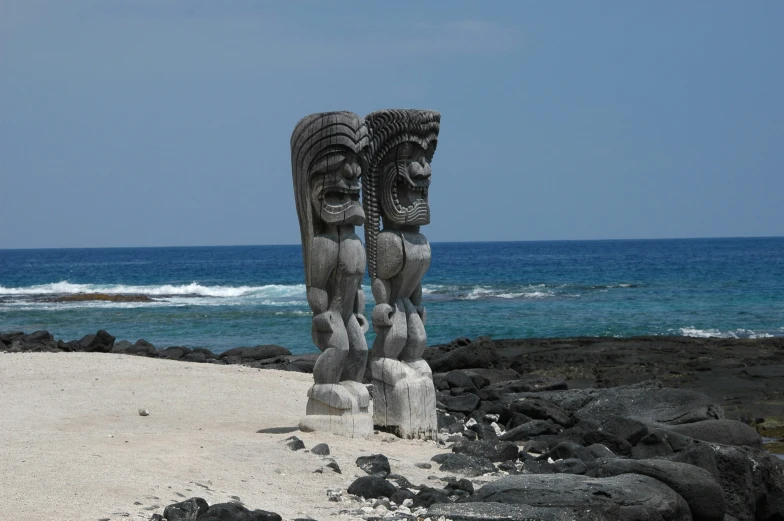 two stone sculptures on the sand of the beach